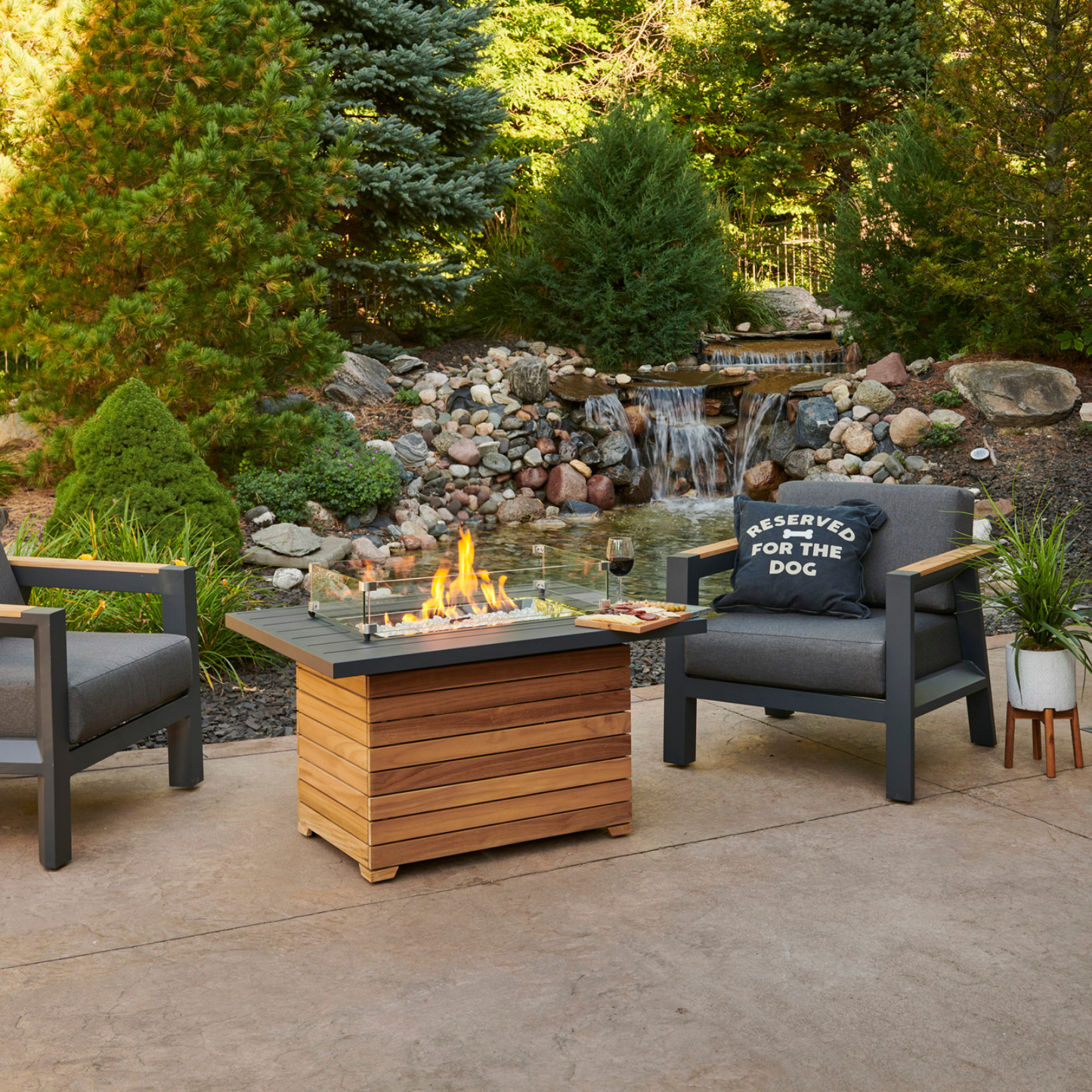 "Add contemporary flair to your outdoor oasis with the Darien Gas Fire Pit Table. Compatible with propane and natural gas, it creates a cozy ambiance. The industrial aluminum top blends seamlessly with the elegant Grade-A teak base, resulting in a distinctive aesthetic that uplifts your exterior décor."